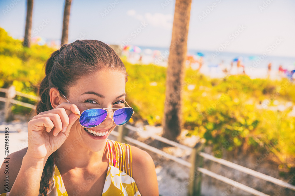Smiling Asian young woman wearing fashion blue sunglasses posing at beach. Summer travel vacation girl relaxing in sun. Smiling Asian young woman wearing fashion blue sunglasses posing at beach. Summer travel vacation girl relaxing in sun.