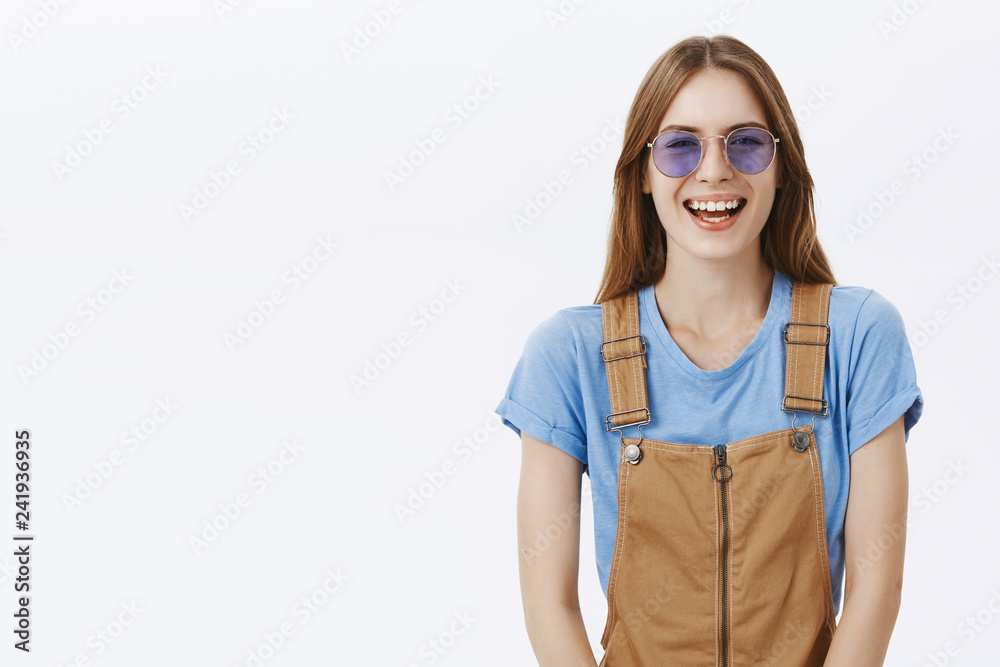 Waist-up shot of charming happy and amused european brunette in brown overalls and stylish sunglasses laughing joyfully having fun talking with friends and enjoying cool sunny day Waist-up shot of charming happy and amused european brunette in brown overalls and stylish sunglasses laughing joyfully having fun talking with friends and enjoying cool sunny day