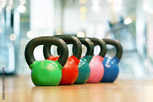 Colorful kettlebells in a row on the wooden floor in a gym. Rows of kettlebells in the gym.