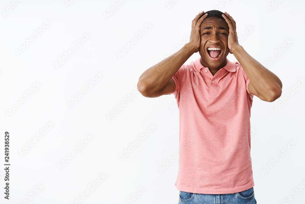Man screaming out loud losing control of feelings, panicking not handling pressure standing troubled and concerned over gray background holding hands on head yelling feeling perplexed Man screaming out loud losing control of feelings, panicking not handling pressure standing troubled and concerned over gray background holding hands on head yelling feeling perplexed