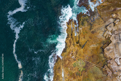 Aerial, overhead view of waves and a rocky shoreline