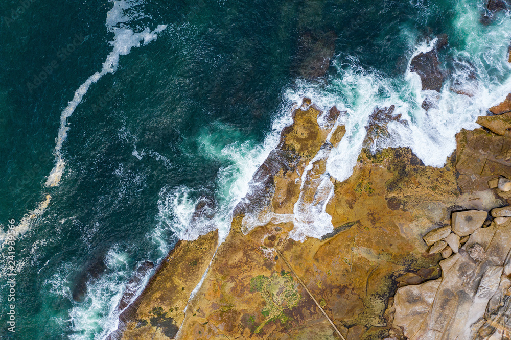 Aerial, overhead view of waves and a rocky shoreline