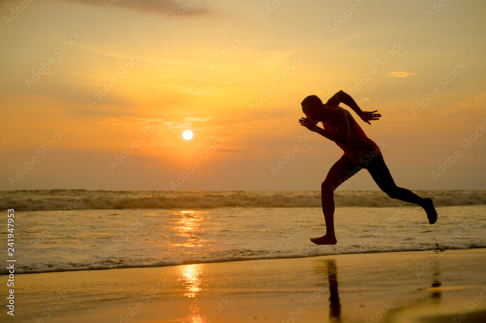 silhouette of young attractive fit athletic and strong black African American man running at sunset beach training hard and sprinting on sea water in runner workout silhouette of young attractive fit athletic and strong black African American man running at sunset beach training hard and sprinting on sea water in runner workout
