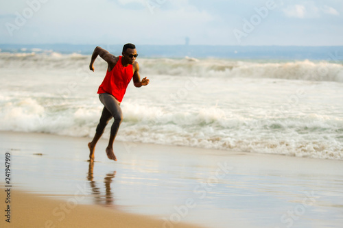 young attractive fit athletic and strong black afro American man running at the beach training hard and sprinting on sea water in professional athlete lifestyle