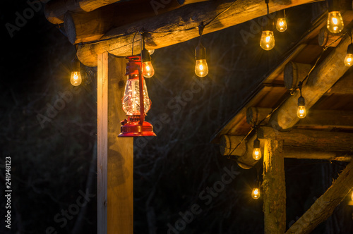 Foto Red metal storm lantern hung outside rustic log cabin.