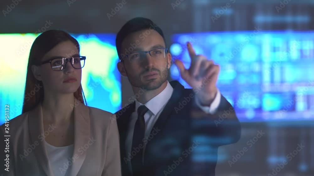 The woman and a man working with a virtual display on the hologram background The woman and a man working with a virtual display on the hologram background