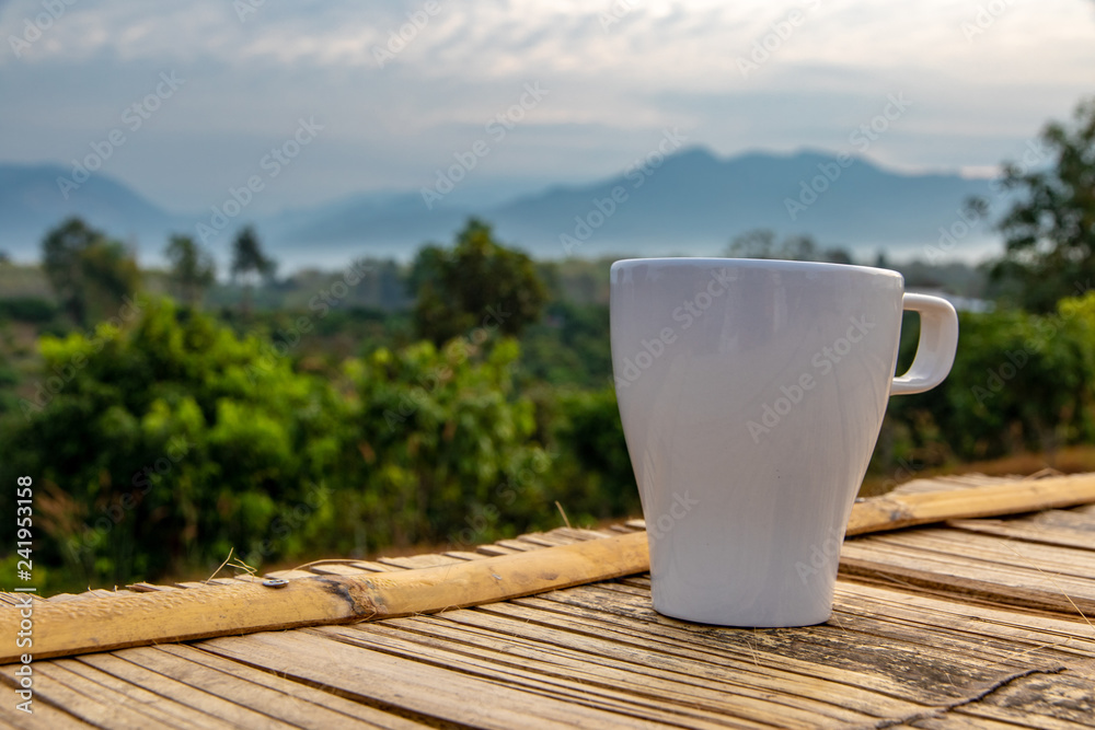 Cup of coffee on bamboo mat and nature background.
