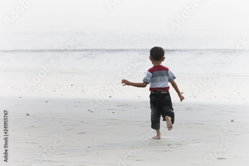 rear of little boy standing looking the sea
