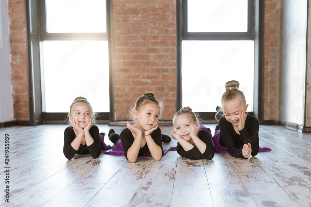 Fototapeta premium Cute little kids dancers on dance studio. Choreographed dance by a group of small ballerinas practicing at a modern ballet school