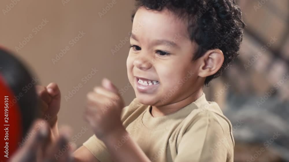 Close up shot of laughing biracial boy trying to fight with childish punching bag at home Close up shot of laughing biracial boy trying to fight with childish punching bag at home