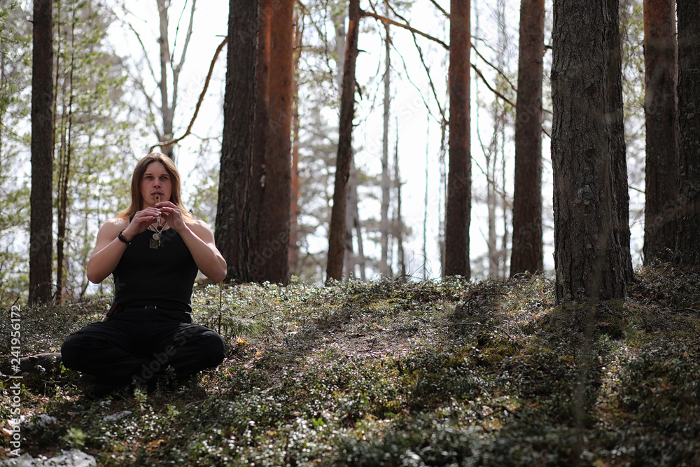A musician with a tool in nature. A man is playing a flute in a pine forest. The music of the druids in the spring forest. A musician with a tool in nature. A man is playing a flute in a pine forest. The music of the druids in the spring forest.
