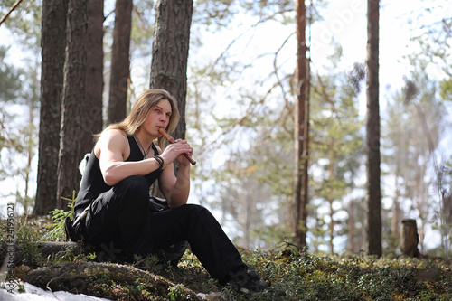 A musician with a tool in nature. A man is playing a flute in a pine forest. The music of the druids in the spring forest.