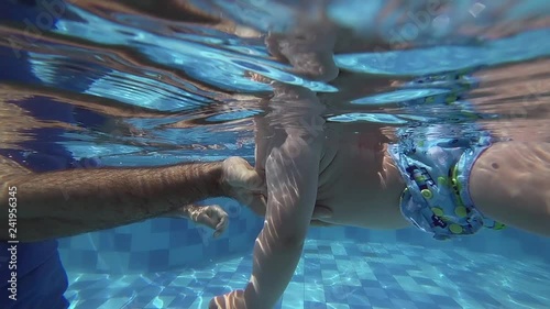 Happy smiling toddler is diving under water with father