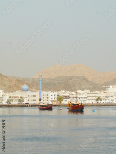 panoramic view on the Muscat corniche with its blue mosque in the back and two traditional dhow boats in the front, Oman, Middle East photo