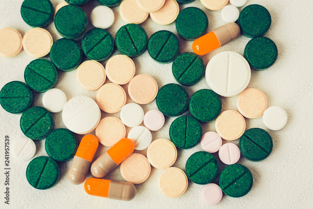 Medicine green, pink and yellow pills or capsules on white background with copy space. Drug prescription for treatment medication. Blister pack. Medicine green, pink and yellow pills or capsules on white background with copy space. Drug prescription for treatment medication. Blister pack.