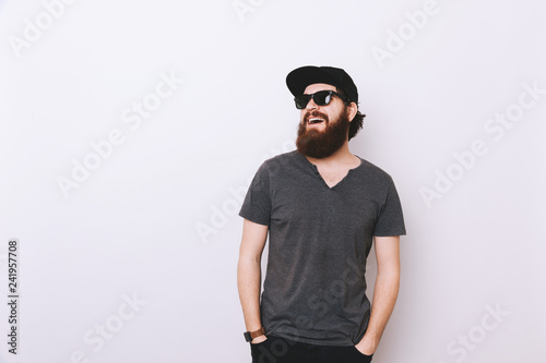 Portrait of happy bearded man in hat and sunglasses looking away