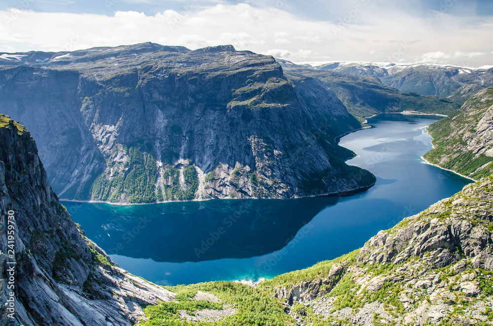 Obraz premium Spectacular view of a blue lake 700 meters lower under the Trolltunga rock and interesting sky with few clouds