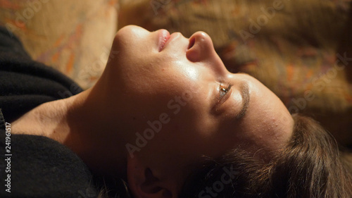 close up profile shoot of a young woman staring at ceiling and dreaming 