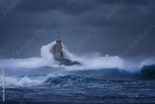 Big wave against old Lighthouse in the port of Ahtopol, Black Sea, Bulgaria on a moody stormy day. Danger, dramatic scene.