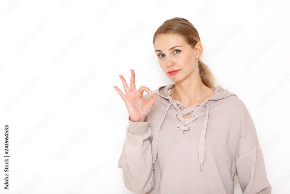 Portrait of a young American woman with blond hair in a gray sweatshirt. She depicts the sign Portrait of a young American woman with blond hair in a gray sweatshirt. She depicts the sign