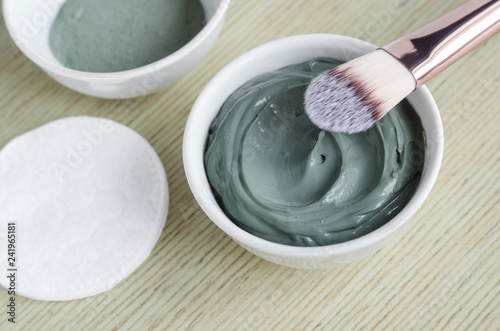 Small white bowl with blue cosmetic clay mask. Homemade beauty treatment. Copy space. 