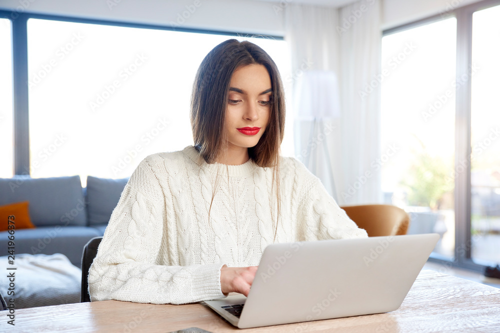 Young woman using laptop while working from home Young woman using laptop while working from home