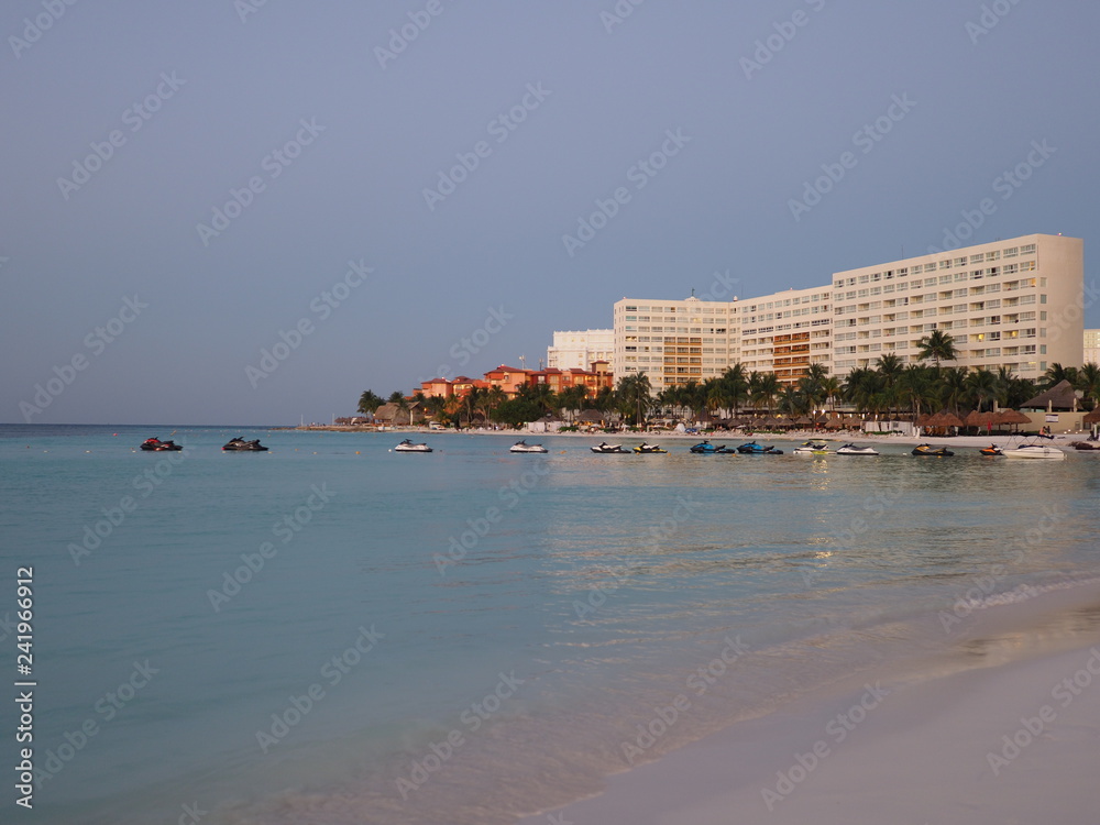 Evening view of white hotels buildings on sandy beach at bay of Caribbean Sea in Cancun city in Mexico