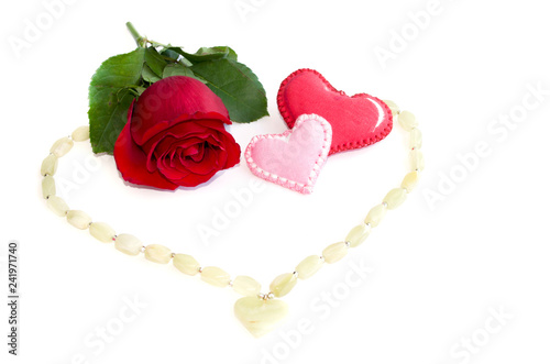 Beads with a pendant in the shape of a heart and a red rose with two textile hearts on a white background