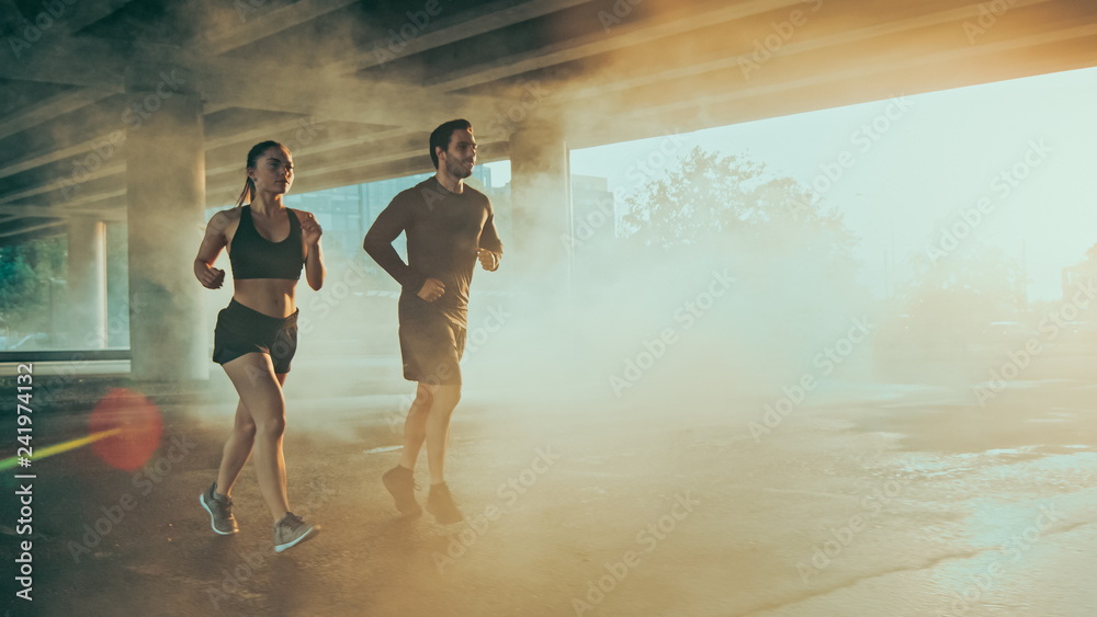 Φωτογραφία Strong and Beautiful Athletic Fitness Couple in Workout Clothes Jogging in a Street Filled With Steam on a Sunny Day
