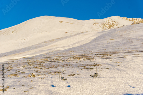 Empty chairlifts in a ski resort going over the snow covered mountain photo