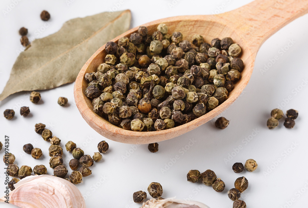 Green peppercorn seeds in wooden spoon on table