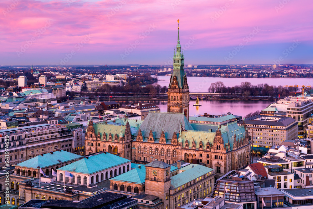 The Hamburg City Hall (German: Rathaus) with downtown and the lake Alster at dusk. Aerial view.