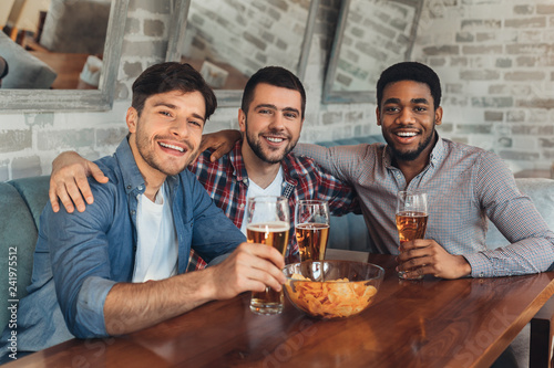 Handsome friends drinking beer, resting at pub