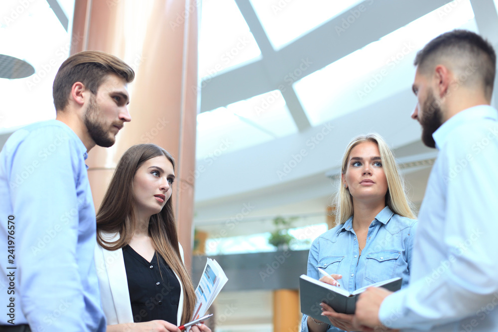 Business discussion. Modern people in casual wear having a brainstorm meeting while standing in the creative office. Business discussion. Modern people in casual wear having a brainstorm meeting while standing in the creative office.