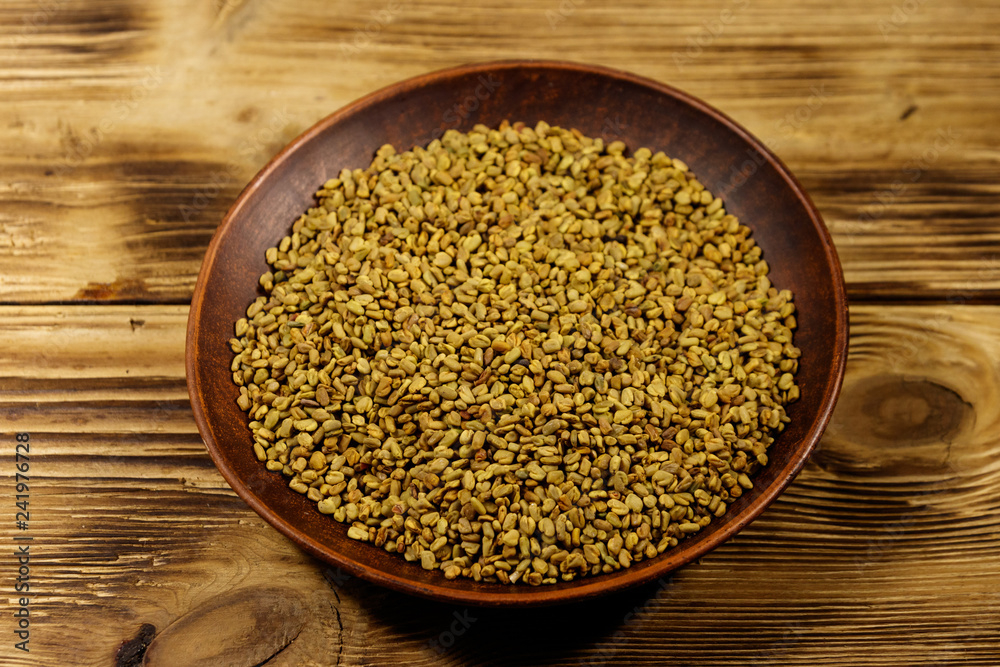 Fenugreek seeds in ceramic plate on wooden table