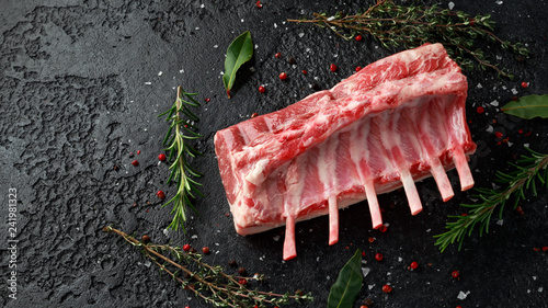 Photos raw fresh rack of lamb with green herbs.