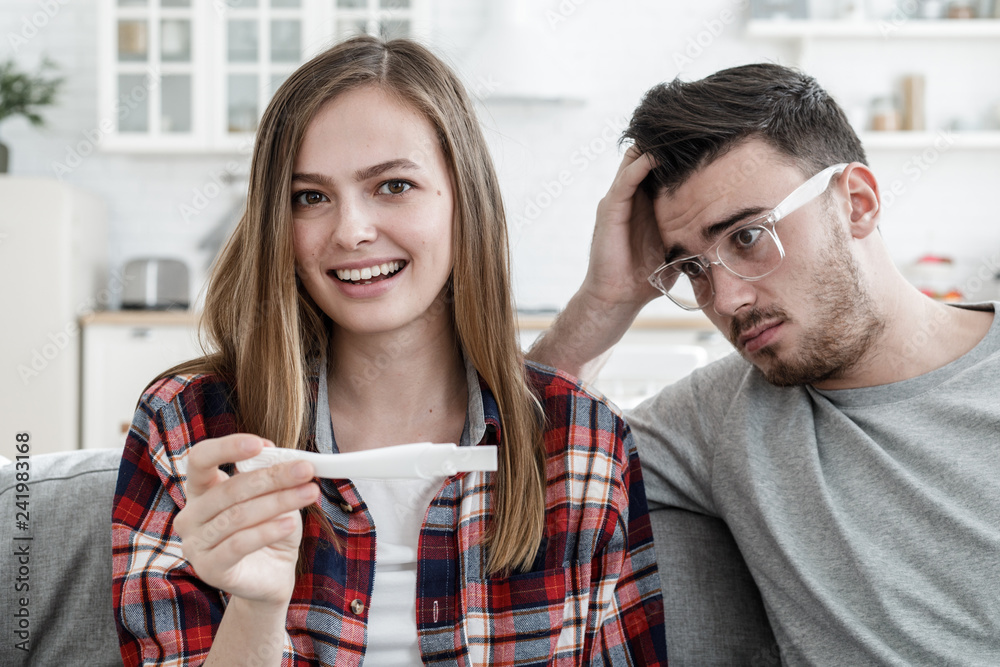 Young lady glad that she has got pregnant and her boyfriend looking worried and frightened with puzzled face not ready for family relationship Young lady glad that she has got pregnant and her boyfriend looking worried and frightened with puzzled face not ready for family relationship