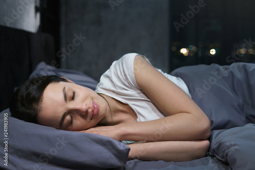 Young female sleeping peacefully in her bedroom at night, relaxing