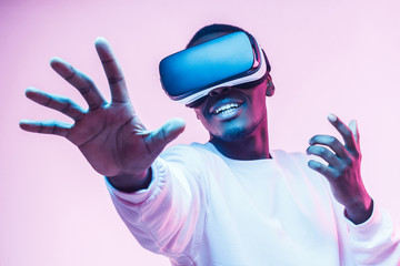 African american man in vr glasses, playing video games with virtual reality headset, trying to touch something with hand