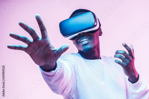 African american man in vr glasses, playing video games with virtual reality headset, trying to touch something with hand photo