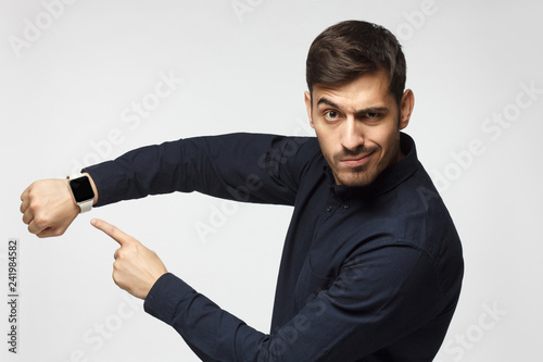 Foto It's time to act! Man pointing at watch with impatience as if asking to hurry up