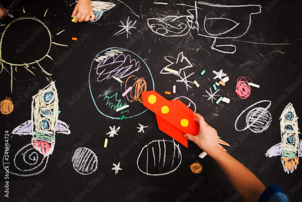 the child draws a rocket and space on a blackboard. preschool Child in creativity in the home.