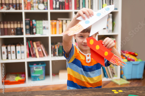 the child holds the rocket made of paper. preschool Child in creativity in the home. Happy kid makes rockets from paper. Children's creativity. photo