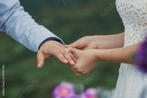 Bride puts a ring on the groom's hand
