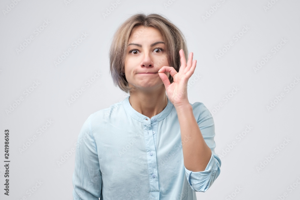 Caucasian pretty woman zipping her mouth shut. Caucasian pretty woman zipping her mouth shut.