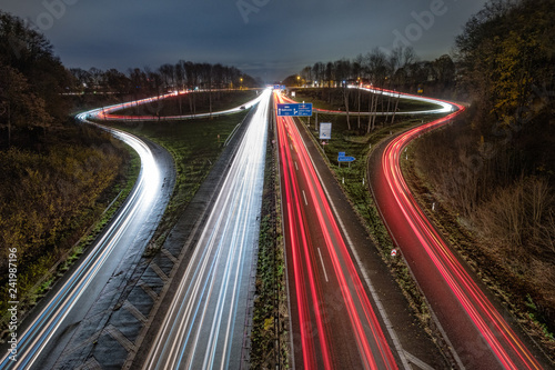 Autobahnausfahrt und Autobahnauffahrt bei Nacht mit Lichtstreifen