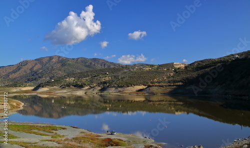 lake in the mountains, beautiful reflections in water, fisherman and his car, blue sky with nice white clouds