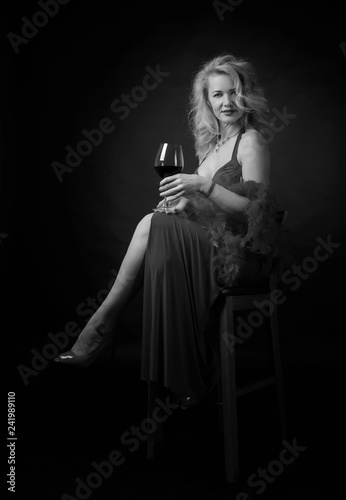 Attractive middle age woman in evening dress with glass of red wine.
