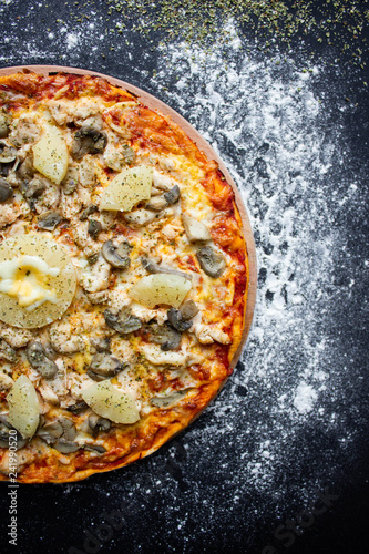 hot tasty delicious rustic homemade american pizza with tomato with thick crust on black table