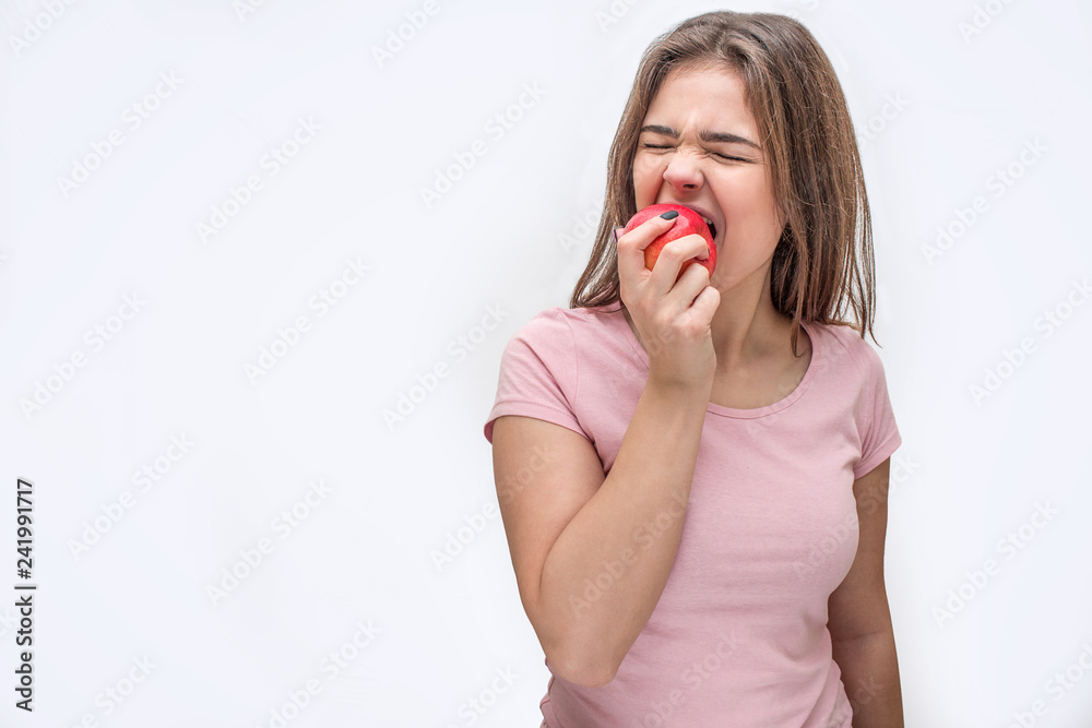 Picture of young woman biting piece from apple. She shrinks. Iolated on white background. Picture of young woman biting piece from apple. She shrinks. Iolated on white background.